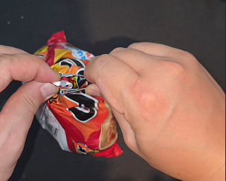 The folded top of a bboggeul-i bag clamped shut with unsplit wooden chopsticks