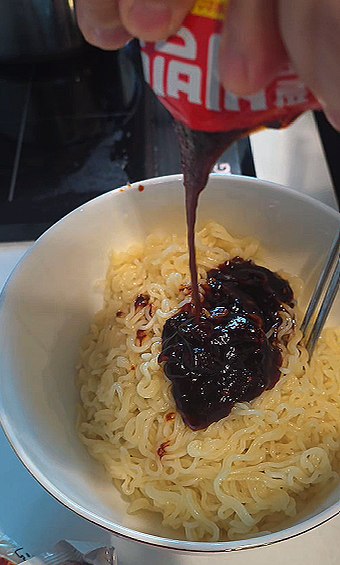 Squeezing the red bibimmyeon sauce onto the rinsed noodles