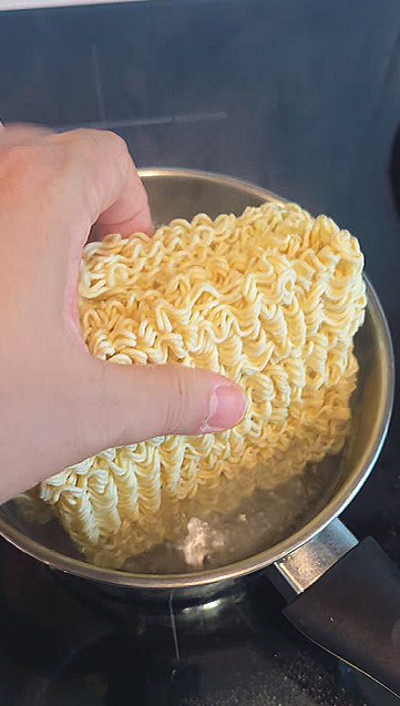 Adding the bibimmyeon noodle blocks to a pot of boiling water