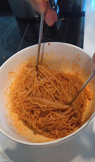 A bowl of Paldo Bibimmyeon mixed with its red sauce, ready to eat