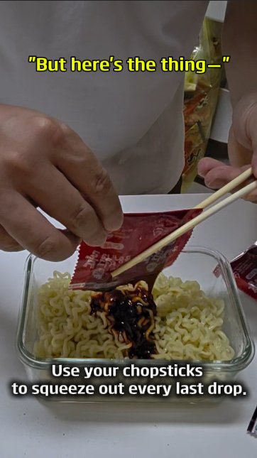 Using chopsticks to squeeze the last of the Buldak sauce packet onto the noodles