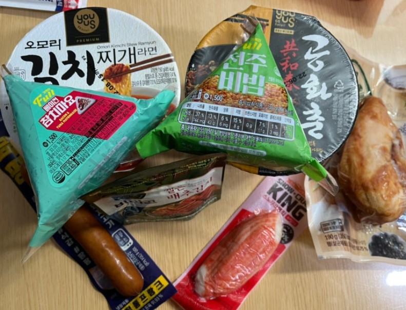 Korean convenience store combos — cup ramyun, triangle kimbap, string cheese, and smoked eggs on a counter