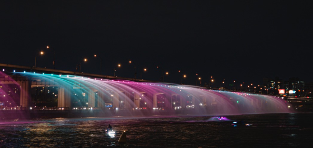 Banpo Bridge Rainbow Fountain at night, water arcing from the bridge lit in pink and blue