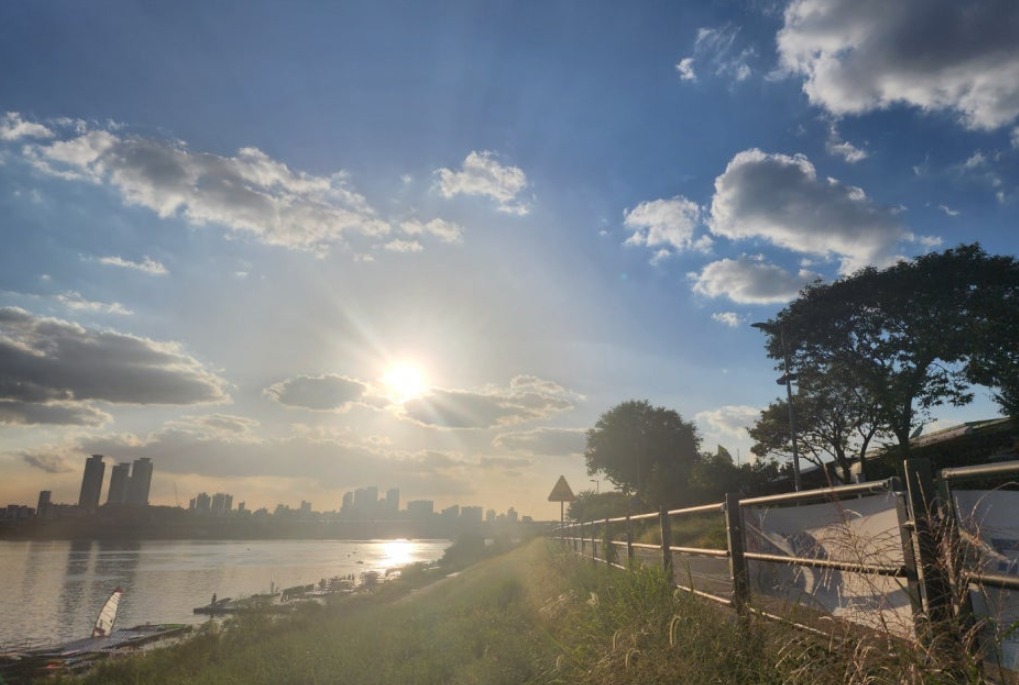 The Han River in the late afternoon with windsurfing boards on the bank and cyclists on the path