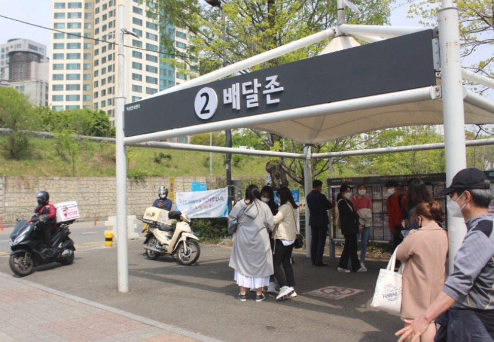 A numbered Delivery Zone sign at a Han River park with delivery motorbikes parked beside it
