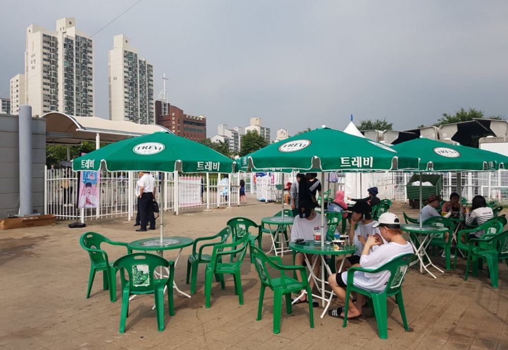 Green parasols and plastic tables outside a Han River convenience store