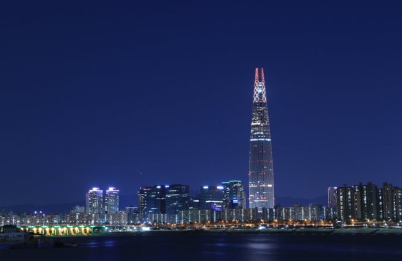 Lotte World Tower lit up at night seen across the Han River from Ttukseom
