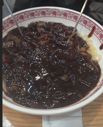 A bowl of jjajangmyeon — Korean black-bean noodles under a glossy dark sauce