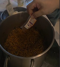 Adding the chili-oil packet and mixing the sauce through the noodles