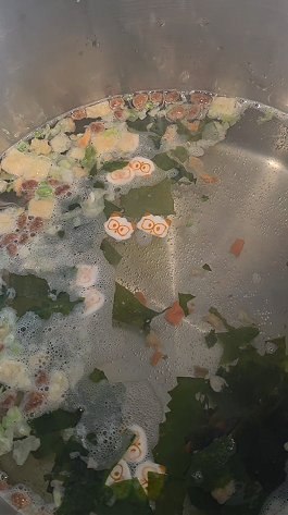 Boiling water with dried vegetable flakes and Neoguri kelp before the noodles soften