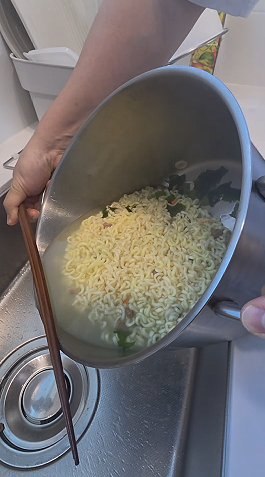 Draining the boiled noodles, leaving a little cooking water in the pot