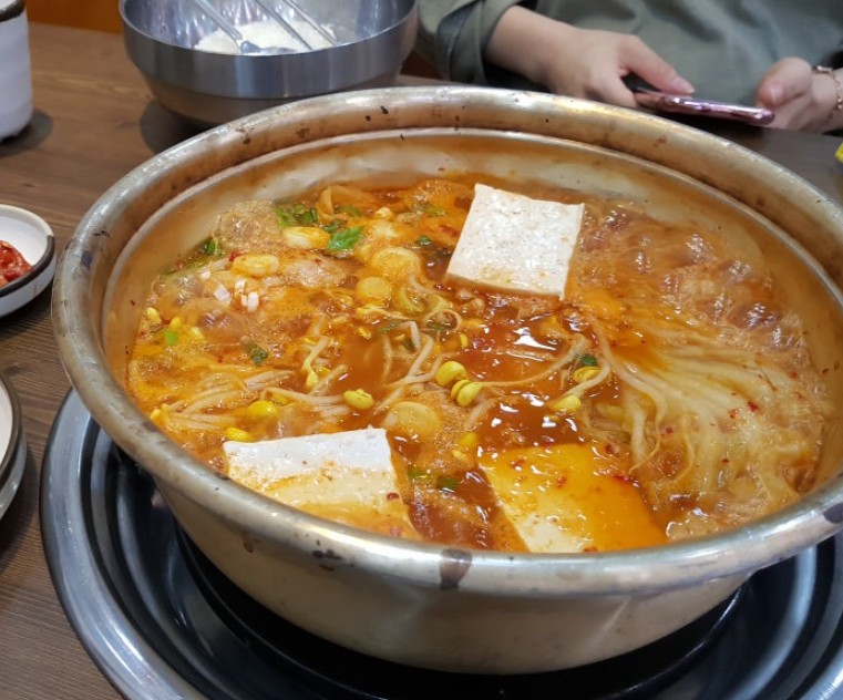 A Korean home meal — ttukbaegi of kimchi jjigae with rice, seaweed, and side dishes