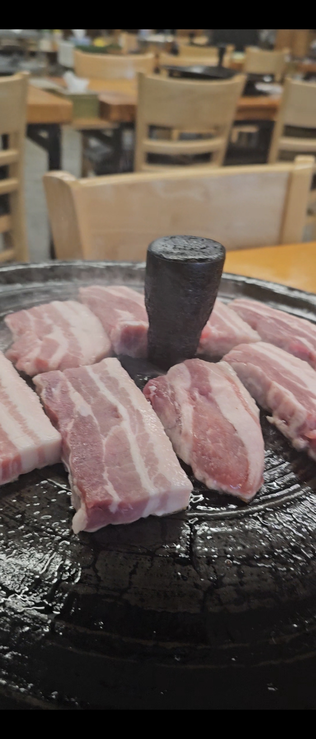 Raw samgyeopsal slices arranged on the grill before cooking at a Korean BBQ restaurant