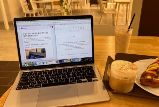A laptop open on a cafe table beside an iced latte and a pastry