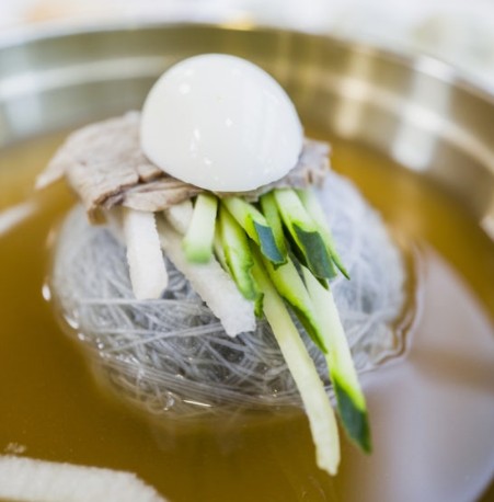 A bowl of naengmyeon topped with thin slices of boiled beef — a mark of a real specialist