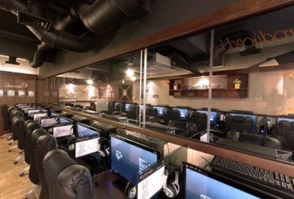 Rows of gaming seats at a Korean PC bang — high-end PCs, curved monitors, and reclining chairs