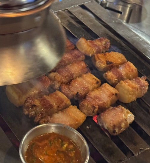 Samgyeopsal grilling over real charcoal (sutbul) at a Korean BBQ restaurant