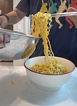 Partially cooked Samyang ramen noodles lifted out of the pot into a bowl