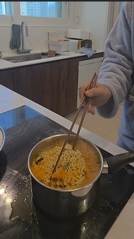 Adding the noodle block to the pot of red broth