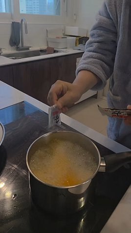 Adding the Shin Ramyun soup powder to the boiling water