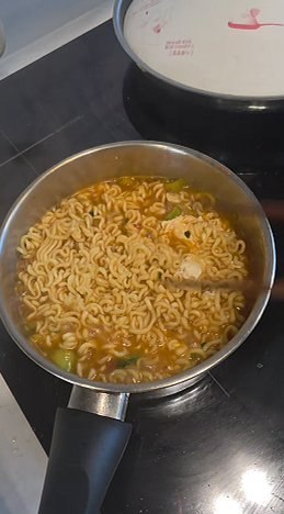 Cooked Shin Ramyun in the pot, noodles glossy in red broth