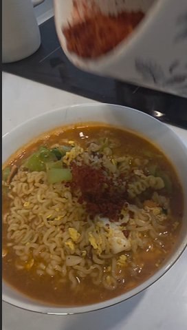 A bowl of Shin Ramyun with green onion, egg, and chili flakes on top