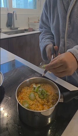 Cutting green onion into the pot with kitchen scissors